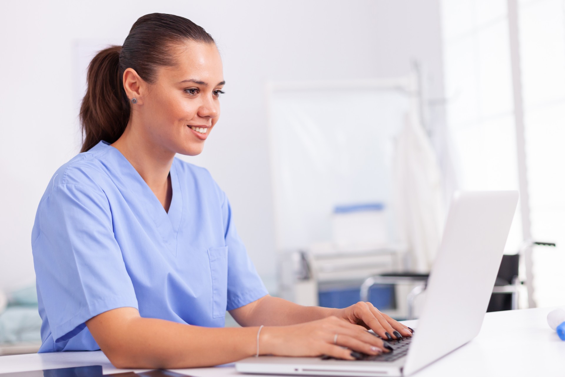 female student at laptop in blue nurse outfit